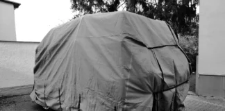 Car under a grey cover parked outdoors for winter storage, a common reason to cancel or suspend car insurance in Ontario
