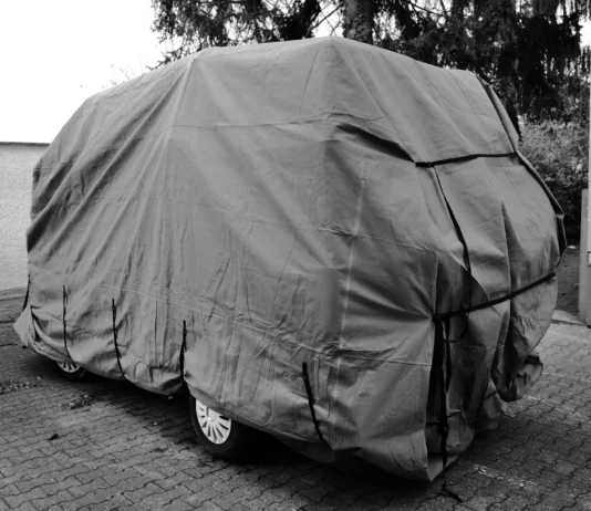 Car under a grey cover parked outdoors for winter storage, a common reason to cancel or suspend car insurance in Ontario